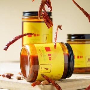 Salsa macha jar over a table with chilis falling down